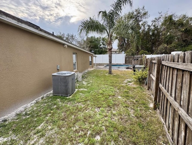 view of yard featuring a fenced in pool and central AC unit