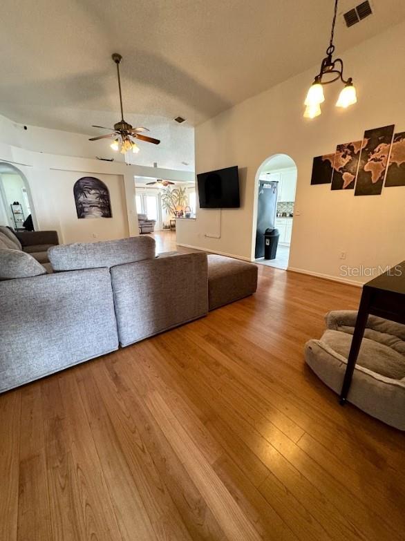 living room with ceiling fan with notable chandelier and hardwood / wood-style floors