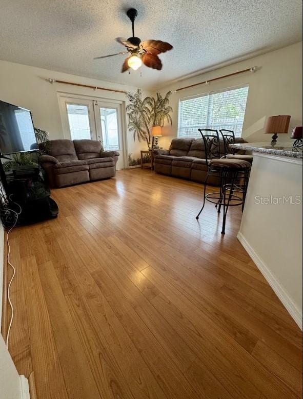 living room featuring light wood-type flooring, a textured ceiling, and a wealth of natural light