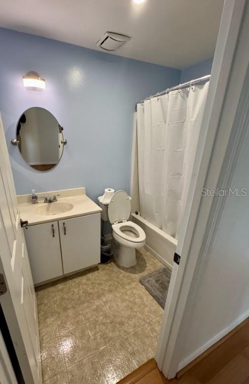 full bathroom with vanity, shower / tub combo with curtain, and toilet