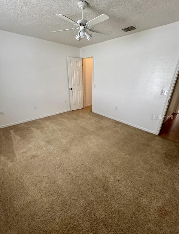 unfurnished room with ceiling fan, carpet, and a textured ceiling