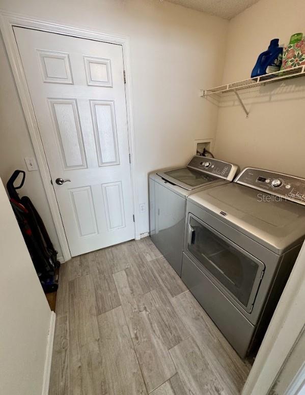 washroom with independent washer and dryer and light hardwood / wood-style floors