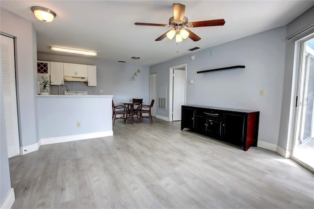 living room featuring ceiling fan, light hardwood / wood-style floors, and sink