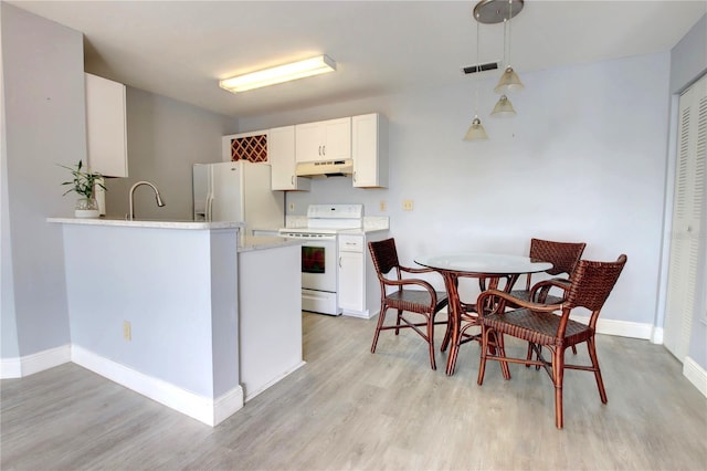 kitchen featuring hanging light fixtures, light hardwood / wood-style flooring, kitchen peninsula, white appliances, and white cabinets