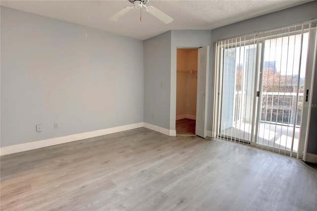 empty room with ceiling fan, a textured ceiling, and light hardwood / wood-style flooring