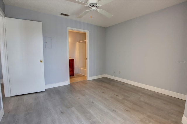 unfurnished bedroom featuring ensuite bath, ceiling fan, and light hardwood / wood-style flooring