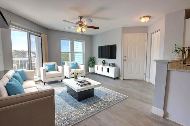 living room featuring ceiling fan, sink, a healthy amount of sunlight, and hardwood / wood-style flooring