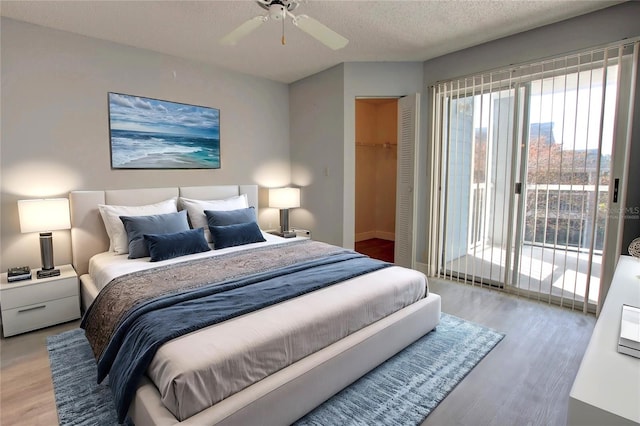 bedroom with access to exterior, a textured ceiling, ceiling fan, hardwood / wood-style floors, and a closet