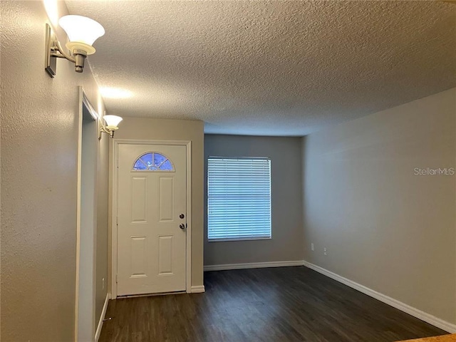 foyer entrance with a textured ceiling and dark hardwood / wood-style floors