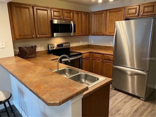 kitchen featuring sink, appliances with stainless steel finishes, kitchen peninsula, and a breakfast bar area