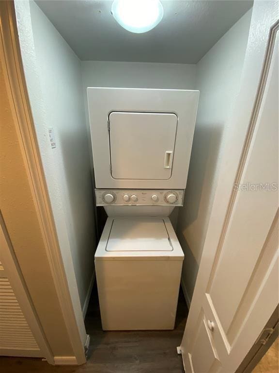 laundry room featuring hardwood / wood-style floors and stacked washer and dryer