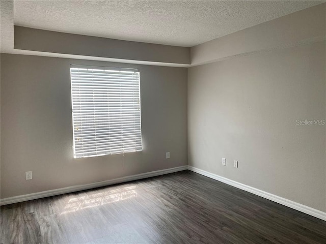 empty room with dark wood-type flooring and a textured ceiling