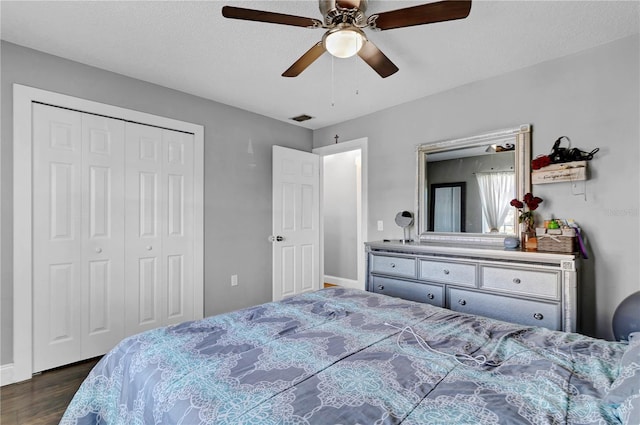 bedroom with ceiling fan, a closet, dark wood-type flooring, and a textured ceiling