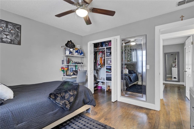 bedroom with ceiling fan, dark hardwood / wood-style floors, a textured ceiling, and a closet