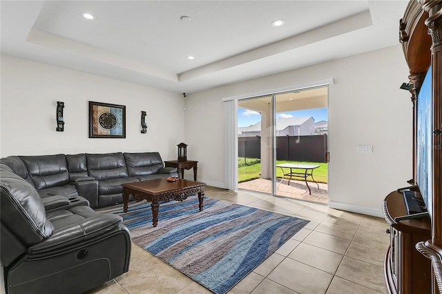 living room featuring a tray ceiling and light tile patterned flooring