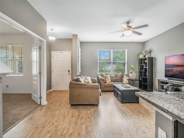 living room with ceiling fan, light hardwood / wood-style floors, and a textured ceiling