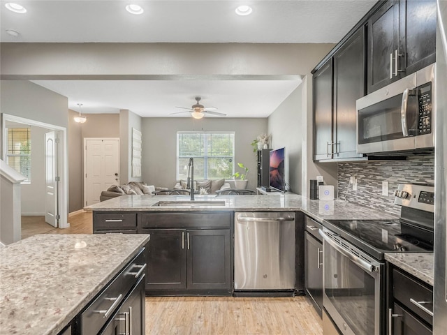 kitchen with backsplash, sink, ceiling fan, appliances with stainless steel finishes, and kitchen peninsula