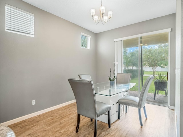 dining space with a healthy amount of sunlight, light wood-type flooring, and an inviting chandelier