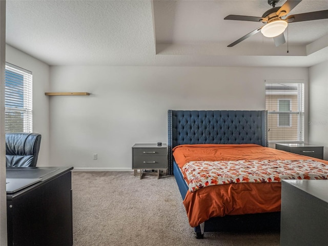 bedroom with carpet floors, a raised ceiling, and ceiling fan