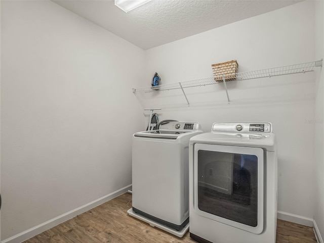 laundry room with wood-type flooring, a textured ceiling, and washing machine and clothes dryer