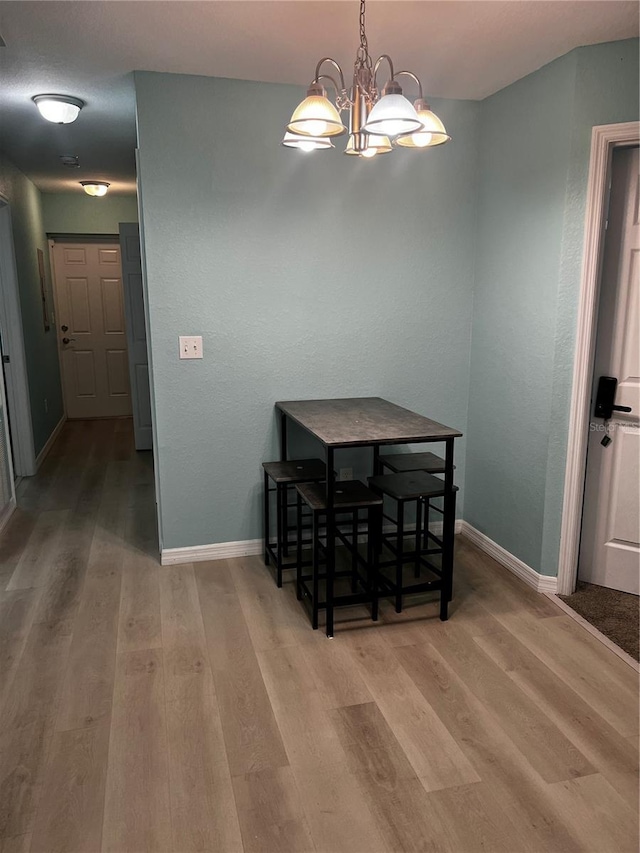 dining area with light hardwood / wood-style floors and a notable chandelier