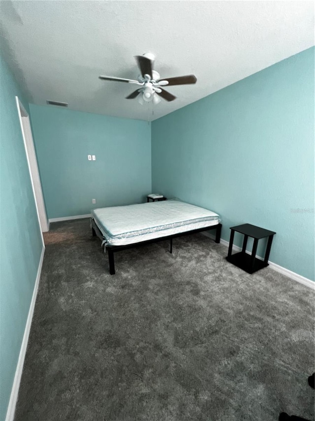 unfurnished bedroom featuring dark colored carpet, a textured ceiling, and ceiling fan