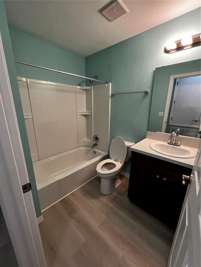 full bathroom with vanity, bathing tub / shower combination, toilet, a textured ceiling, and wood-type flooring