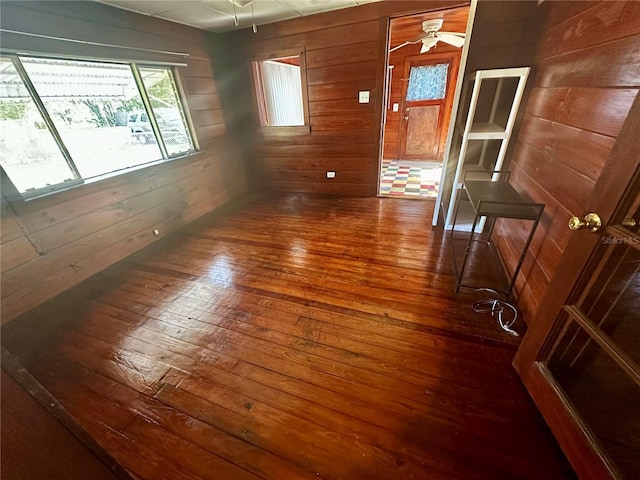 empty room featuring wood walls, ceiling fan, and dark hardwood / wood-style floors