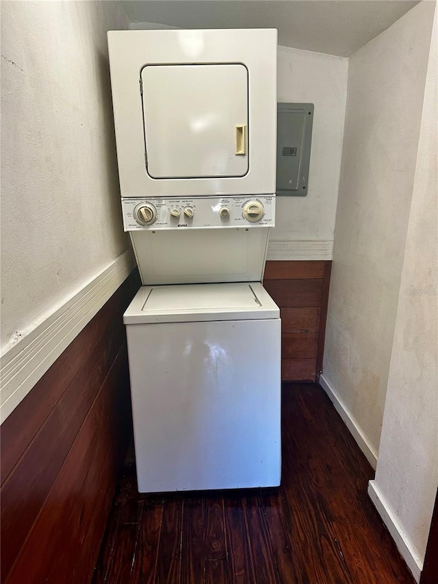 laundry room featuring dark hardwood / wood-style floors, stacked washer and dryer, and electric panel