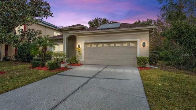 view of front of house with a yard, a garage, and solar panels