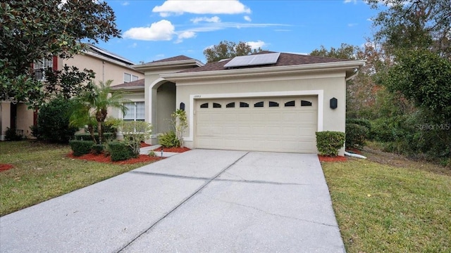 view of front of property with a garage, a front yard, and solar panels