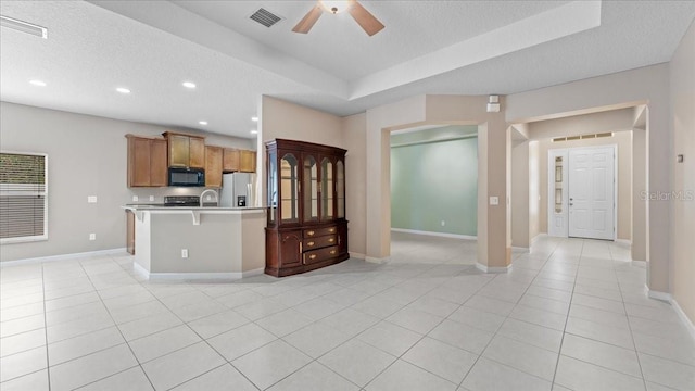 kitchen with stainless steel refrigerator with ice dispenser, a breakfast bar, a textured ceiling, and light tile patterned floors