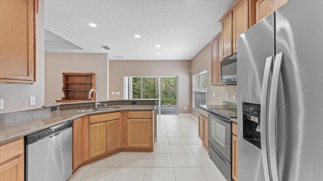 kitchen featuring sink, dark stone counters, light tile patterned floors, black appliances, and a textured ceiling