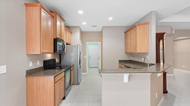 kitchen featuring a breakfast bar, black appliances, sink, light tile patterned floors, and kitchen peninsula