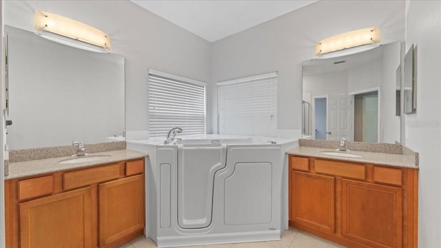 bathroom featuring vanity, a washtub, and tile patterned floors