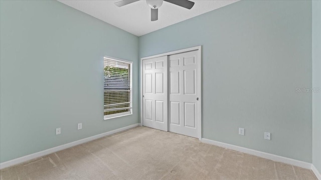 unfurnished bedroom featuring ceiling fan, a closet, and light carpet