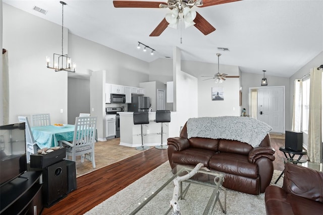 living room with hardwood / wood-style floors, vaulted ceiling, and an inviting chandelier