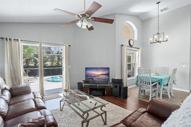 living room featuring ceiling fan with notable chandelier, dark hardwood / wood-style flooring, lofted ceiling, and a textured ceiling