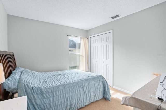 carpeted bedroom featuring a textured ceiling and a closet