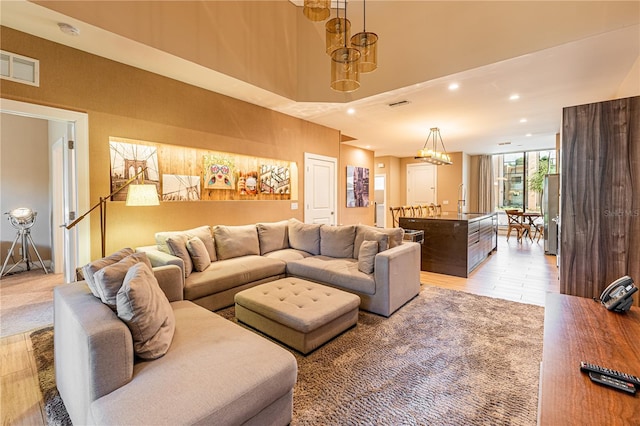 living room featuring sink, a chandelier, and a high ceiling