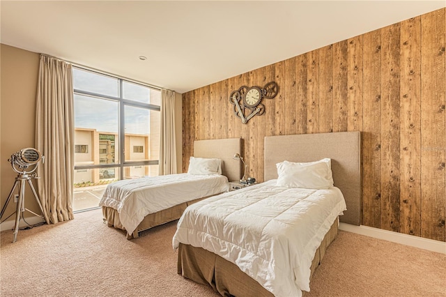 bedroom featuring carpet flooring, floor to ceiling windows, and wood walls