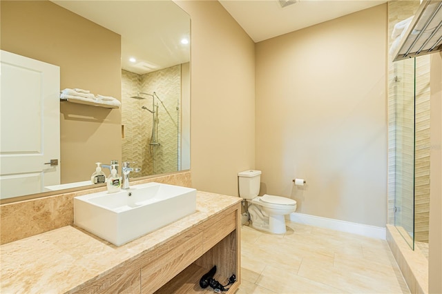 bathroom featuring a tile shower, tile patterned floors, vanity, and toilet