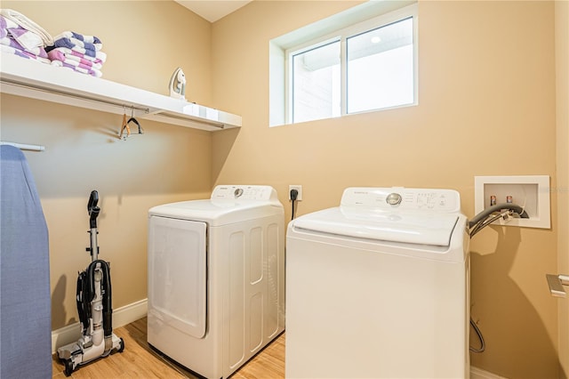 clothes washing area with independent washer and dryer and light wood-type flooring