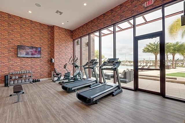 exercise room with hardwood / wood-style floors, expansive windows, and a high ceiling