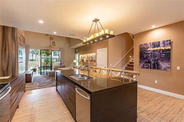 kitchen with a sink, open floor plan, appliances with stainless steel finishes, an island with sink, and dark countertops