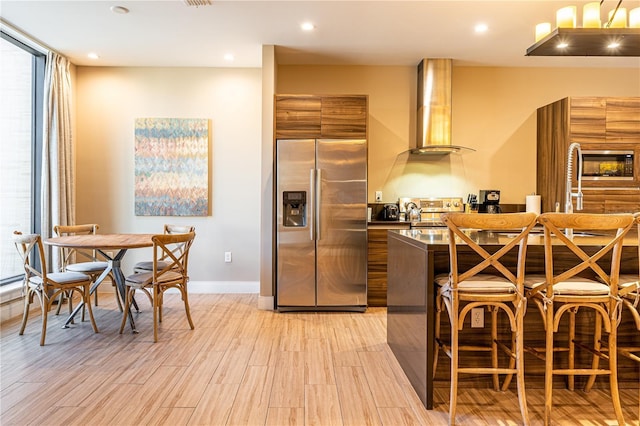 kitchen featuring dark countertops, modern cabinets, light wood-type flooring, built in appliances, and exhaust hood