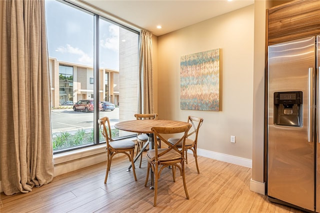 dining space featuring baseboards, light wood-style flooring, and a healthy amount of sunlight