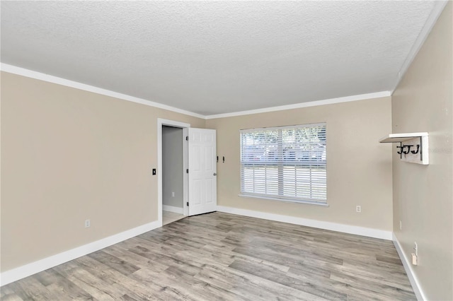 spare room featuring crown molding, a textured ceiling, and light hardwood / wood-style flooring