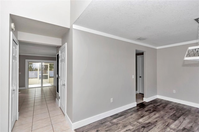 tiled spare room featuring a textured ceiling and crown molding