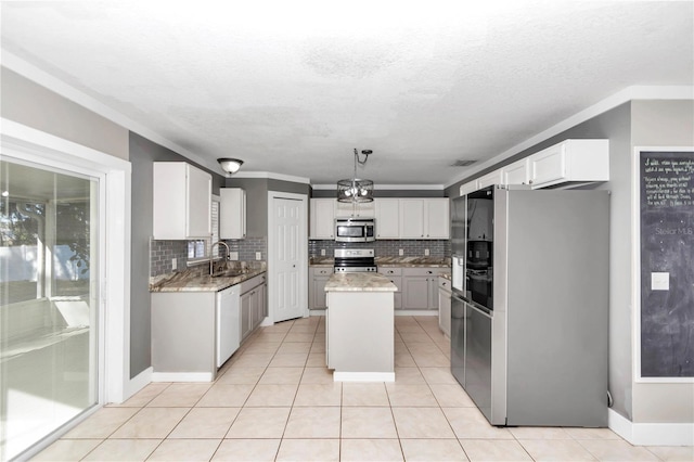 kitchen with white cabinetry, appliances with stainless steel finishes, hanging light fixtures, a kitchen island, and sink